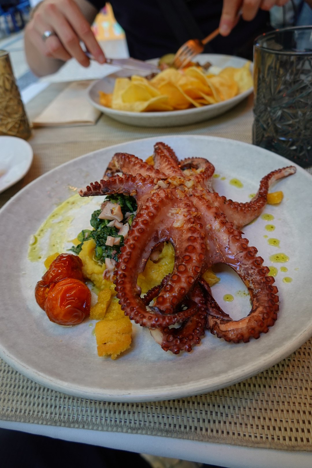 A whole grilled octopus plated with sweet potato purée and roasted tomatoes at a Lisbon restaurant