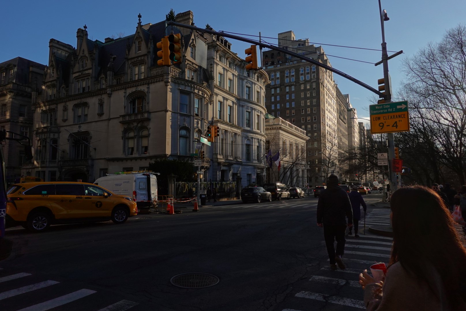 Yellow taxi at a sunlit Upper West Side intersection beside a grand Beaux-Arts building