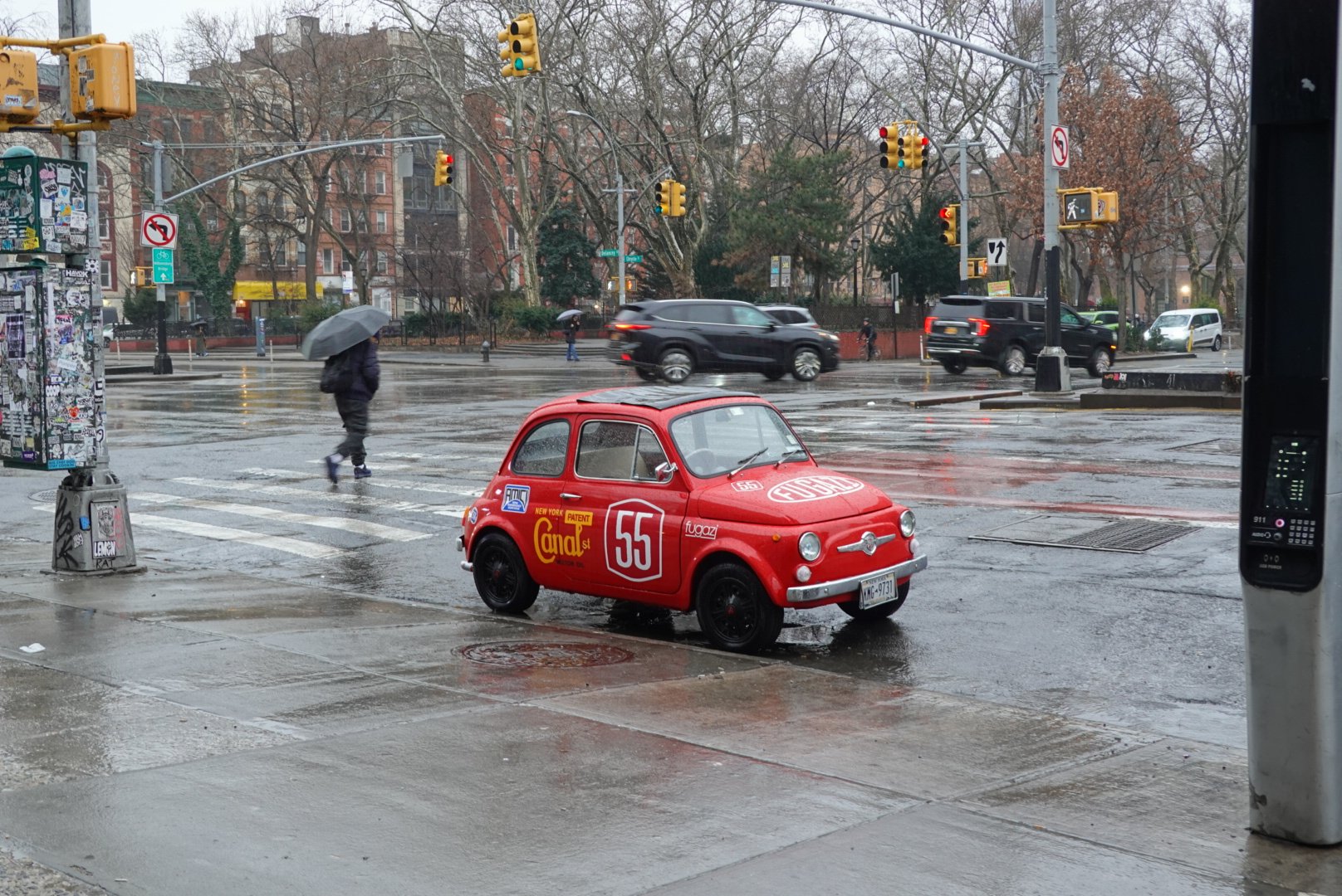 Bright red vintage Fiat 500 racing car parked at a wet Manhattan crossroads on a rainy day