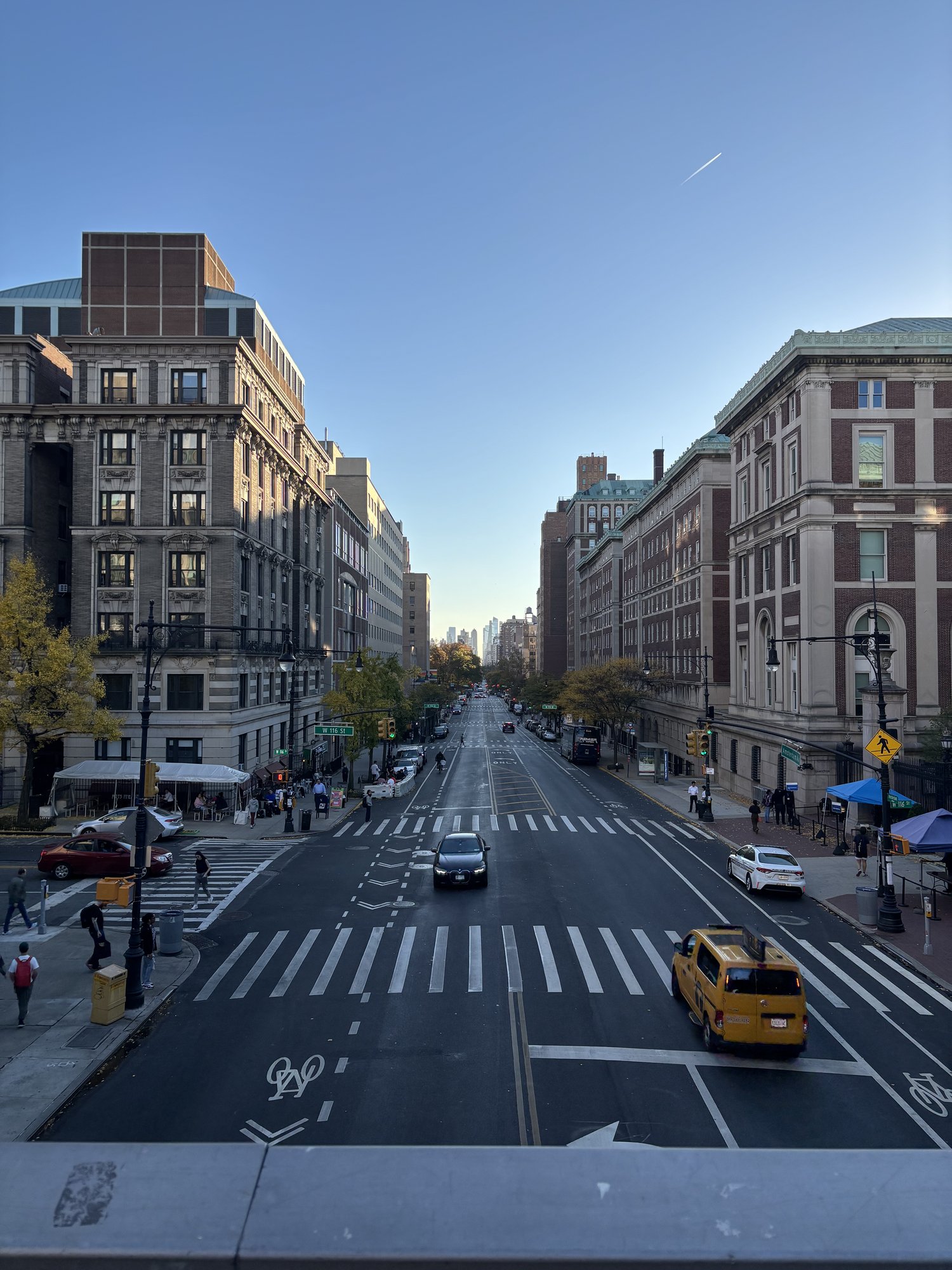 Looking south down a wide Manhattan avenue flanked by Columbia University buildings on a clear autumn day